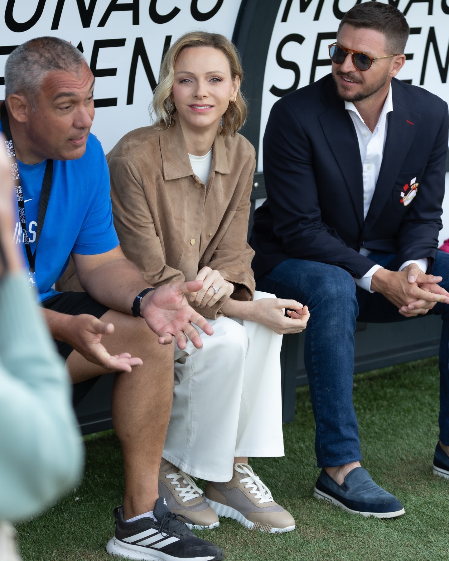 Princess Charlene sitting on a bench with two men