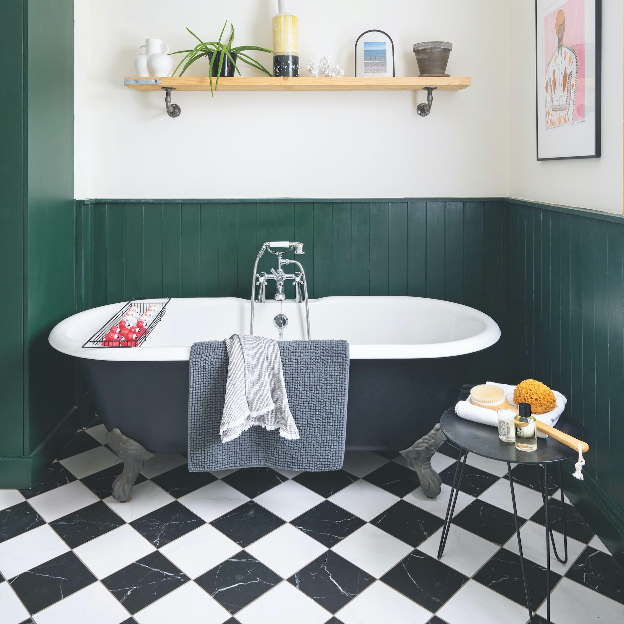 green panelled bathroom with black bath and black and white floor tiles