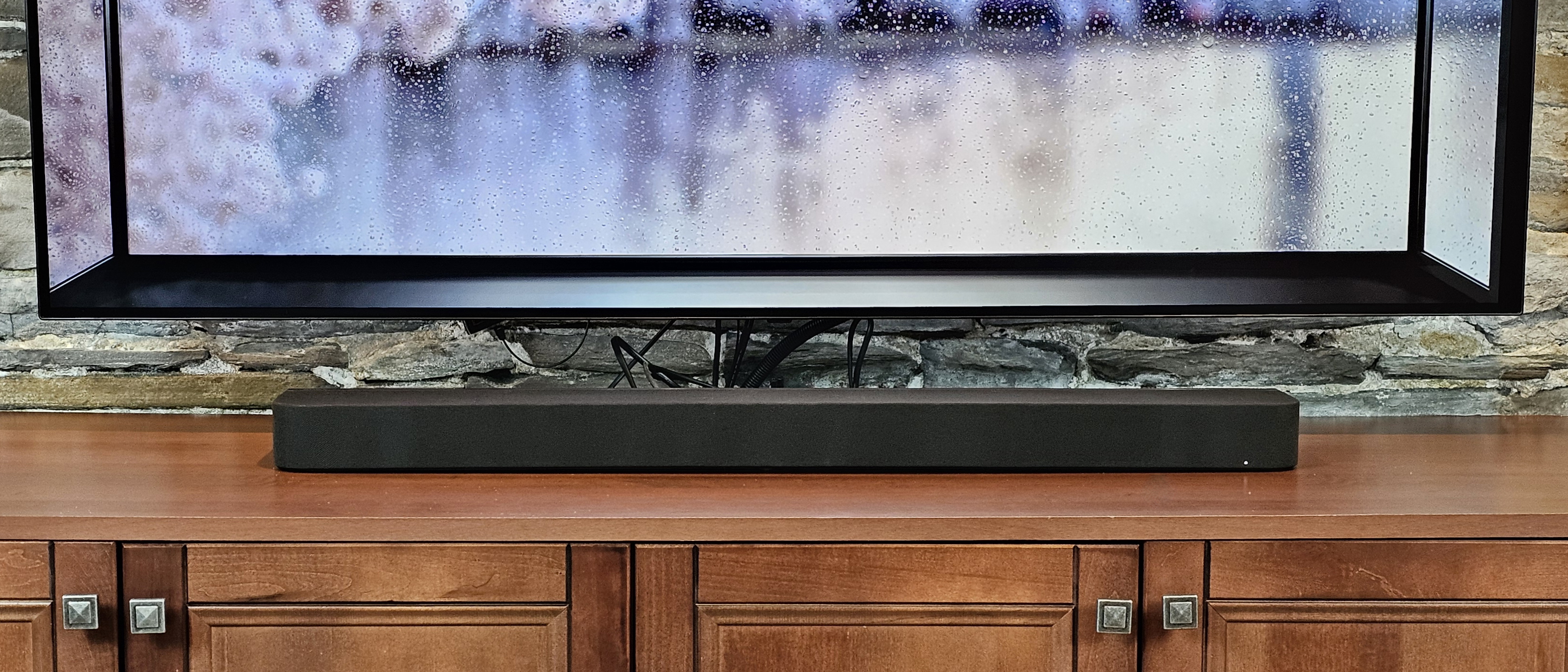 The Sony Bravia Theater Bar 7 pictured under a TV on a wooden cabinet