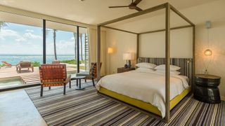 A four-poster bed, striped carpet and large windows in a presidential room at Andaz Mayakoba Resort Riviera Maya