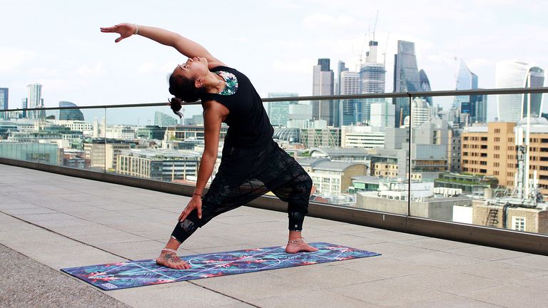 best yoga mat: Woman doing yoga on Form Pro Travel yoga Mat on a rooftop with London skyline in the background