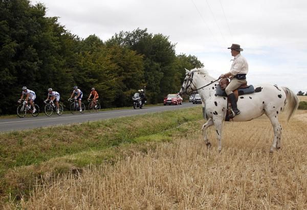 A man on horseback watches the peloton roll by