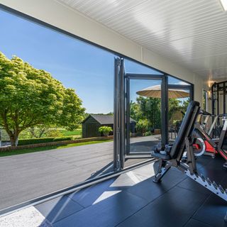 View from exterior of Green Retreats garden room with home gym equipment