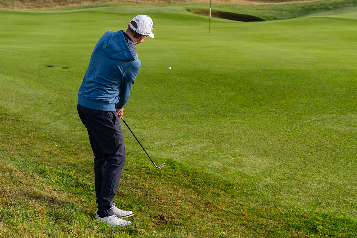 Ben Emerson hitting a bump and run shot, with the ball bouncing just on the front of the green in line with the pin on the 10th hole at Trump Turnberry