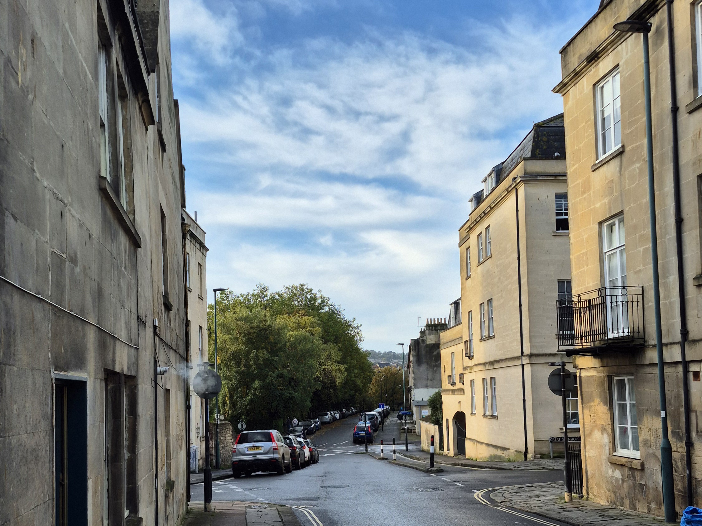 A street scene with a blue sky and sandy limestone terraced buildings