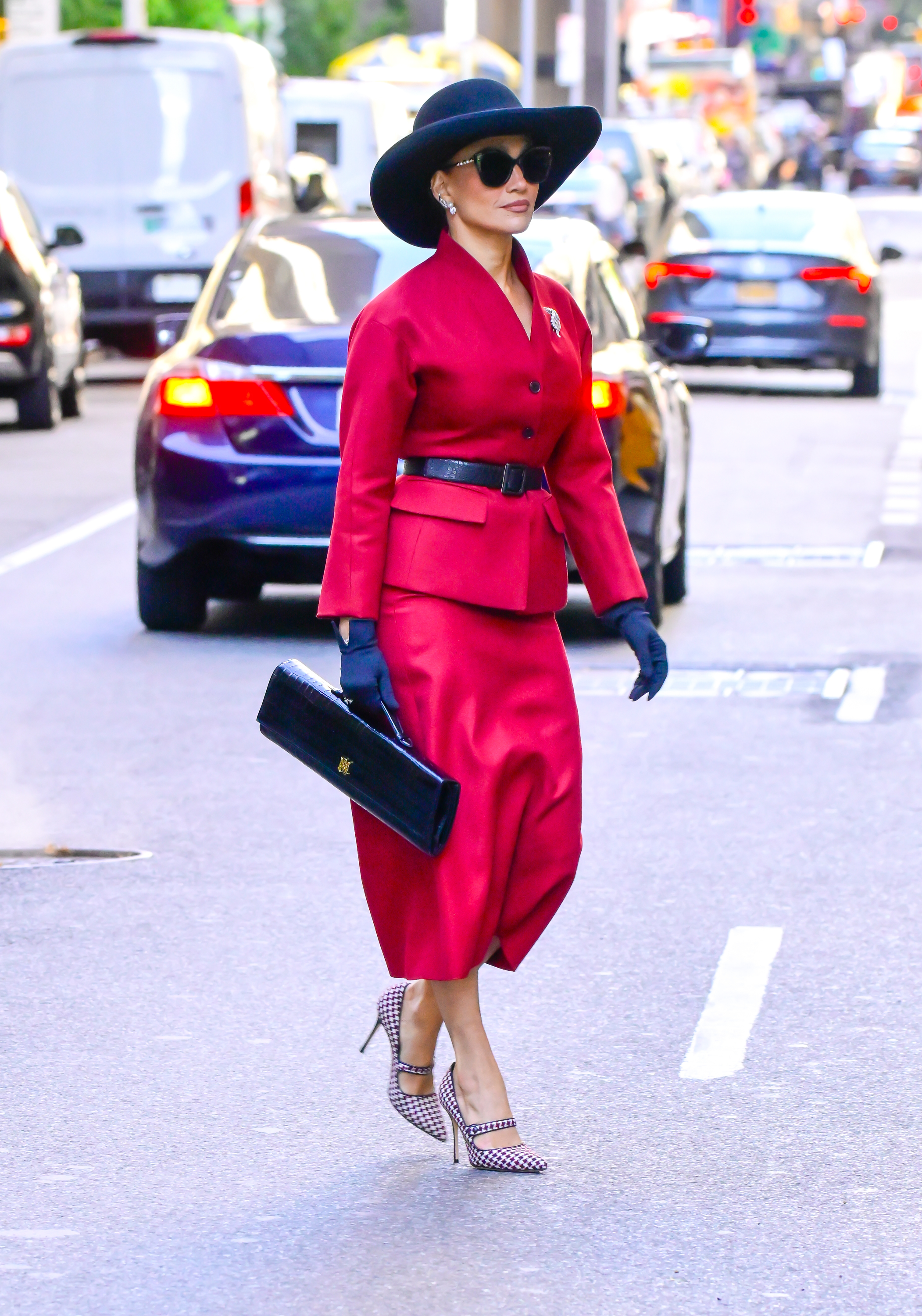 Jennifer Lopez was spotted on the set of her new movie wearing a burgundy skirt set, a croc-embossed bag, a hat, and checkered Mary Janes