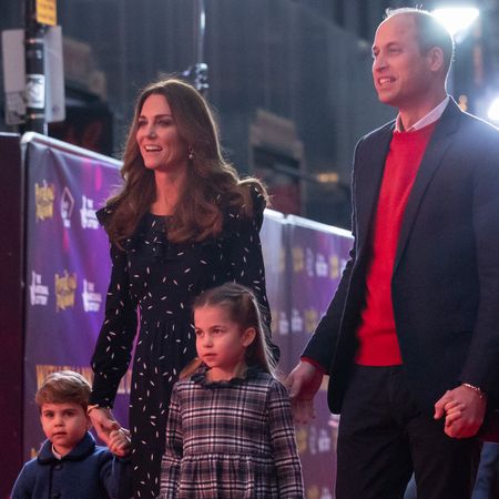 Kate Middleton wears a long-sleeved polka dot dress while Prince William wears a suit jacket with a red sweater, as they hold hands with their kids, Prince George, Princess Charlotte, and Prince Louis