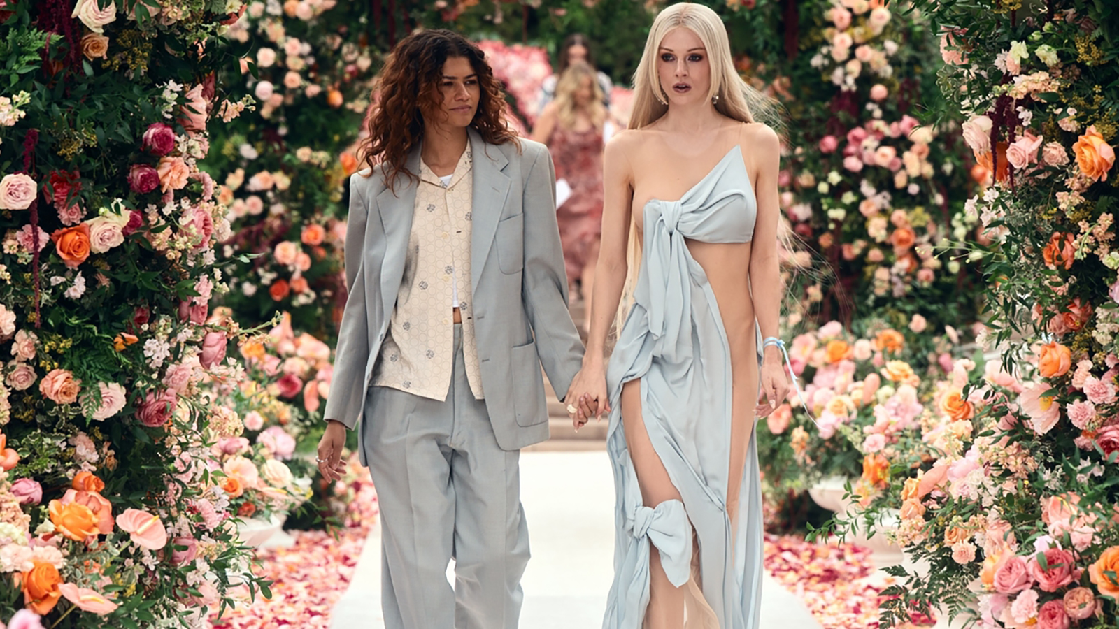 A dishevelled Rue and Jules walking down a flower-filled wedding aisle in Euphoria season 3 episode 3