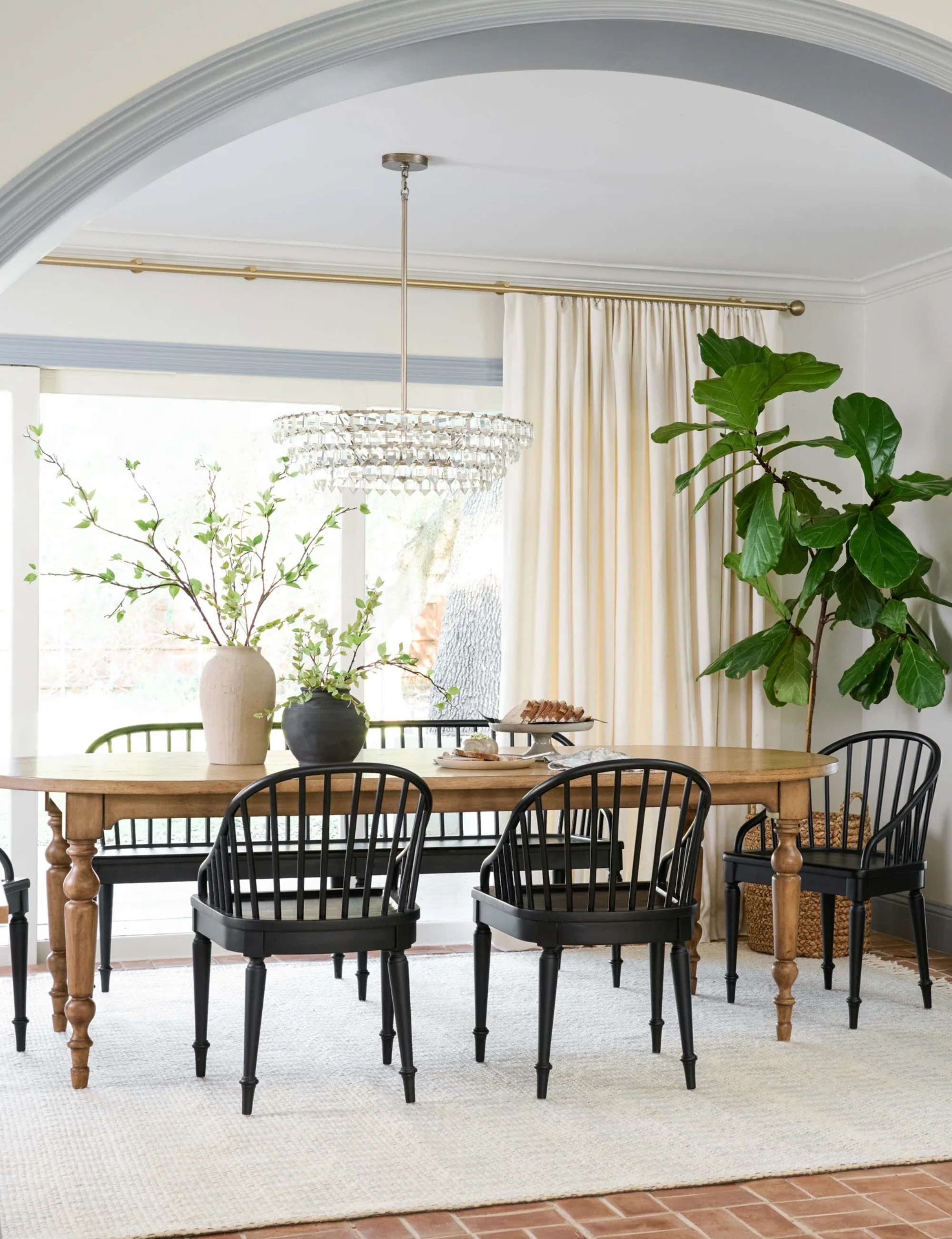 a dining room with a large table and black dining chairs and a plant in the corner