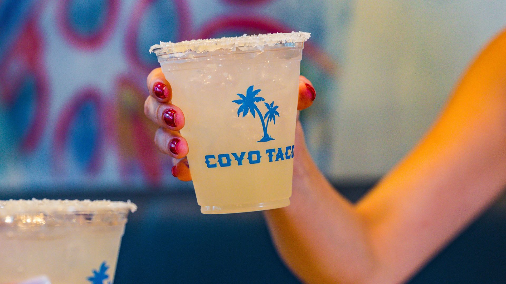 an image of a woman holding a frozen margarita from Coyo Taco