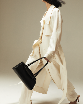 Woman wearing all white while carrying black Caroline Freja NYC bag.