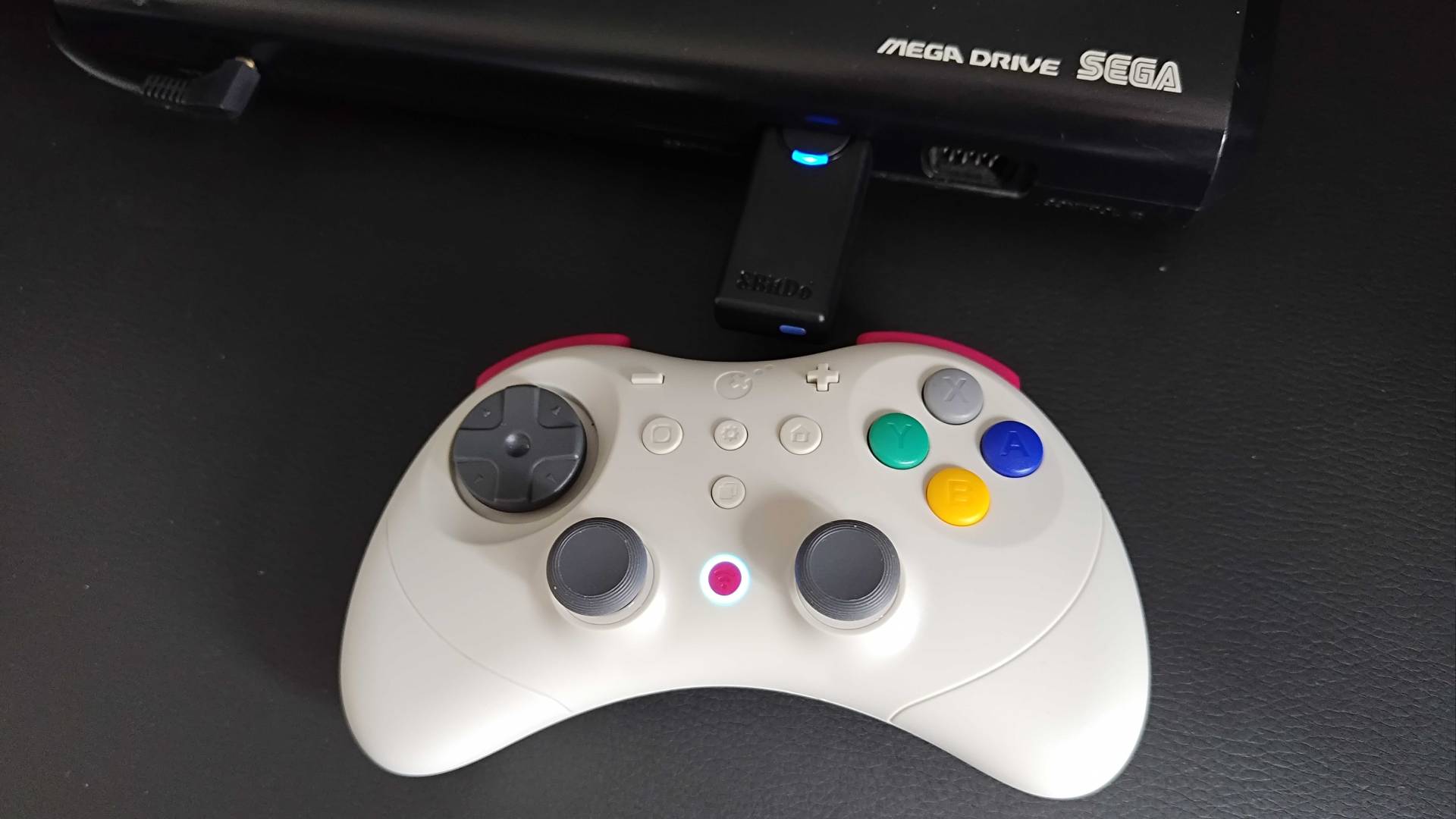 Gulikit Elves 2 Pro next to Sega Mega Drive with synced 8Bitdo Retro Receiver in controller port 1.