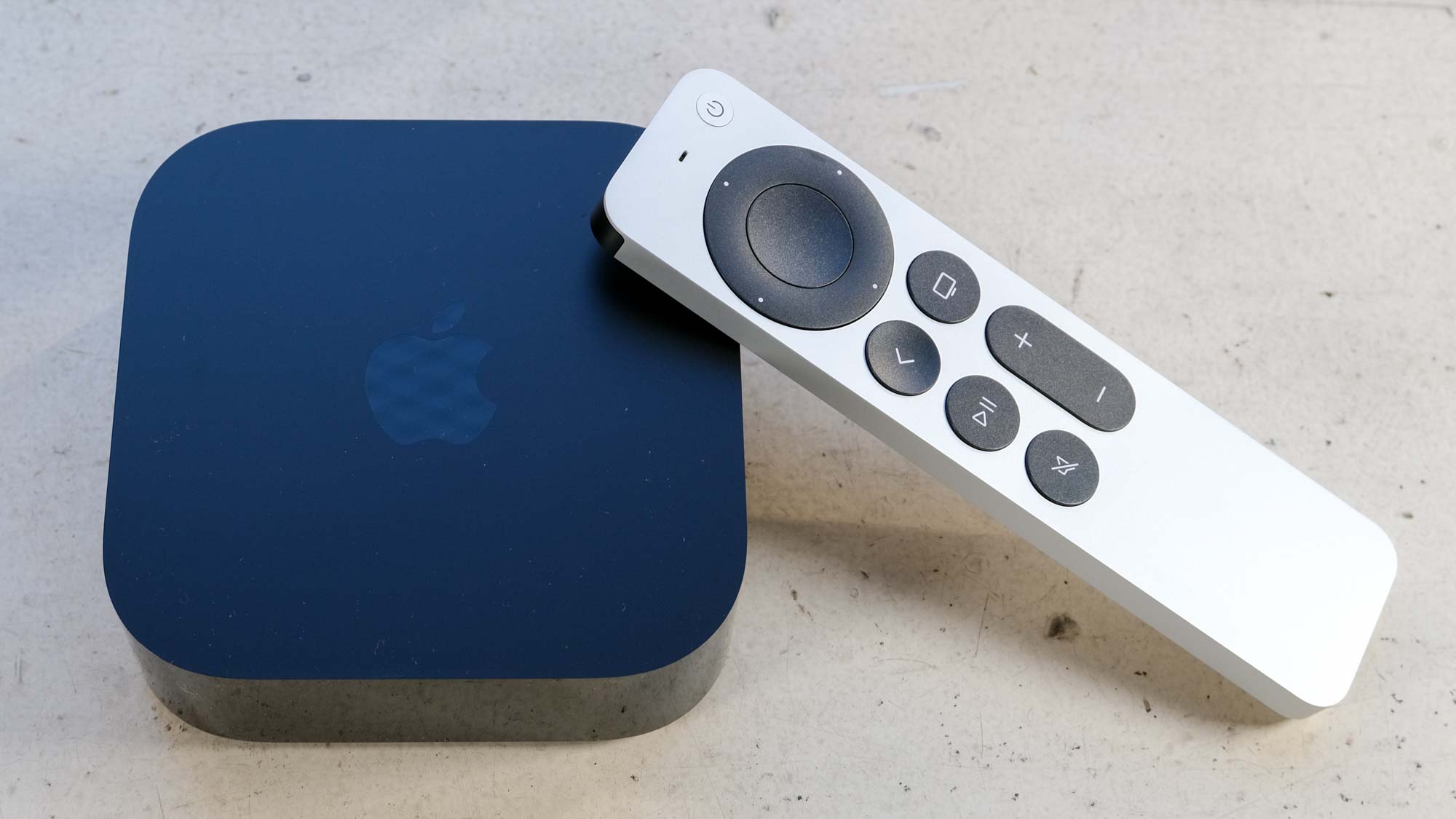The Apple TV 4K (2022) is on a white surface, with its remote propped against it.