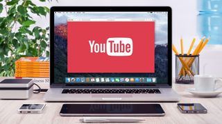MacBook Pro ouvert sur un bureau avec le logo YouTube sur l'écran