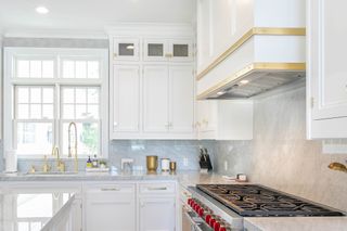 white kitchen with gold chandelier and hardware, and chrome appliances