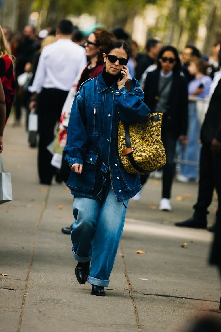 a woman at paris fashion week wearing a denim jacket with blue cuffed jeans