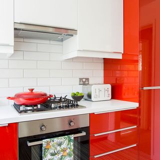 kitchen with white tiles wall white and red cabinets and kitchen stove
