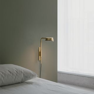 A bedside light attached to the wall with an overhanging lamp.