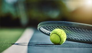 A green tennis ball and racket on top of a tennis court