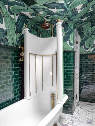Green bathroom with green metro tiles and banana leaf wallpaper on the ceiling