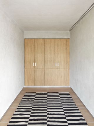 Wooden floor with a black and white carpet and wooden cupboards