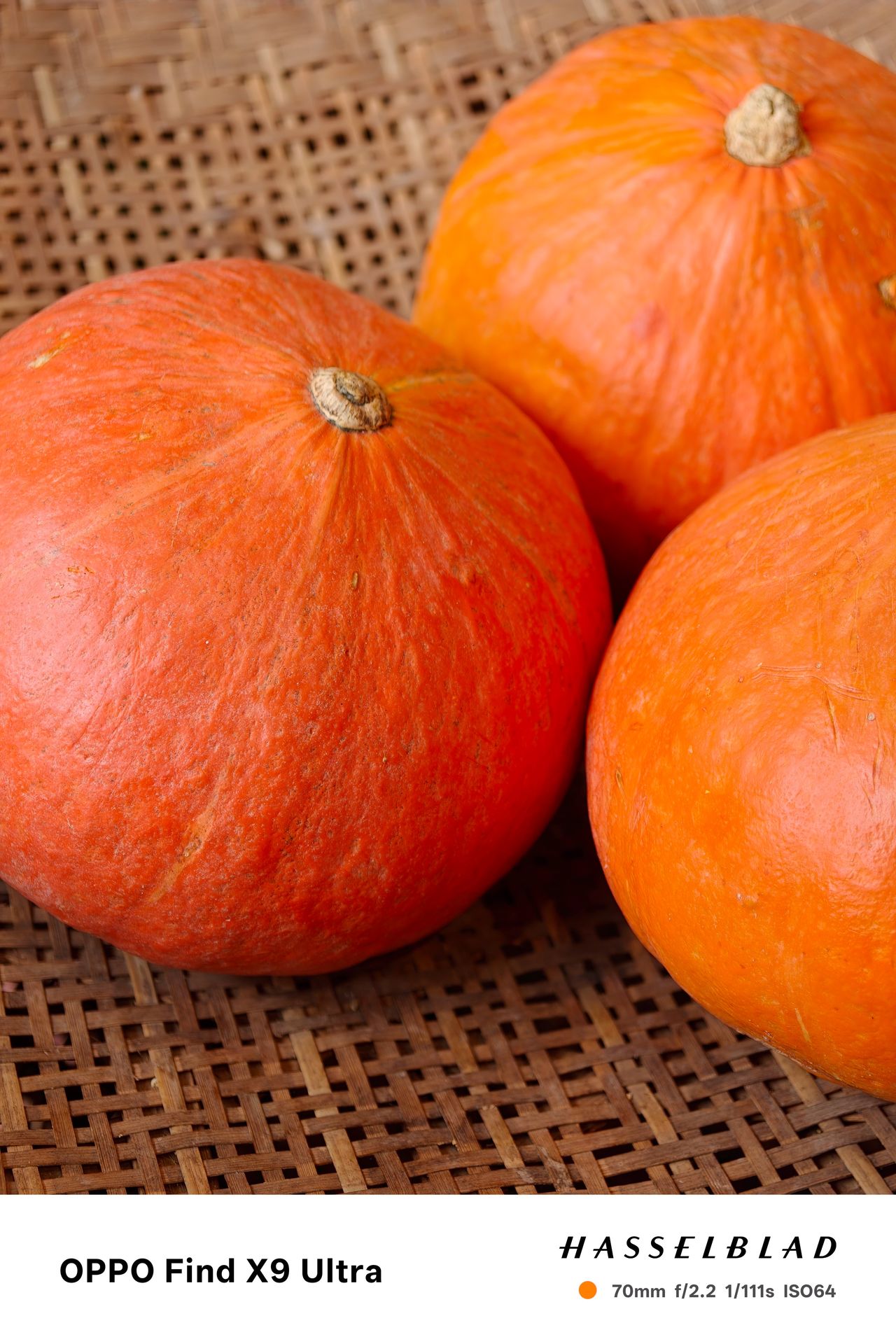 Three bright orange pumpkins resting on a woven wicker surface