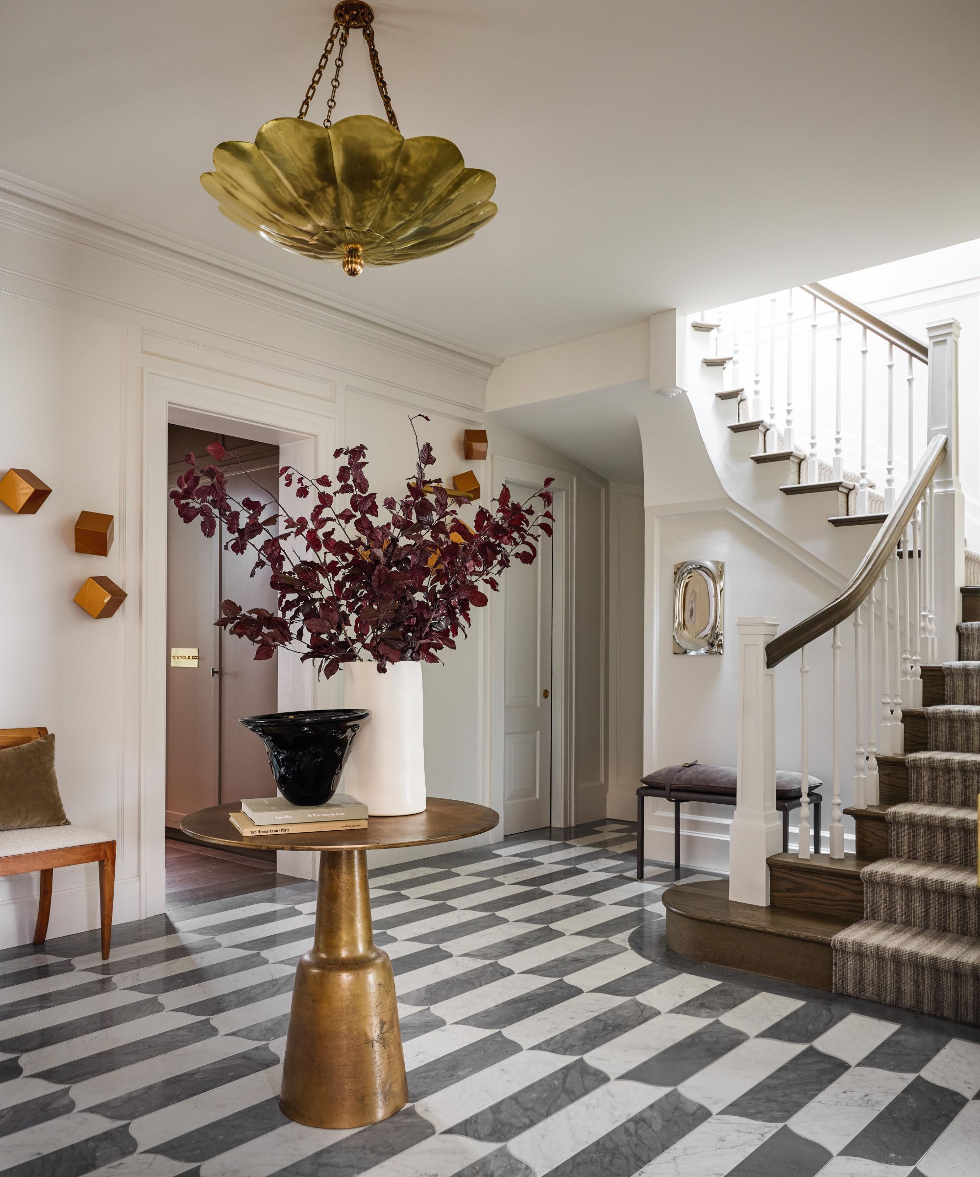 the large entry to a San Fran home with black and white tiled floor, sweeping stairs, brass hall table and overhead light