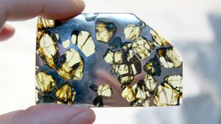 A person holds up a unique mineral with silver reflective and yellow transparent sections