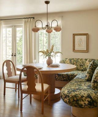 neutral kitchen corner with a floral banquette seat and wooden table with wavy chairs