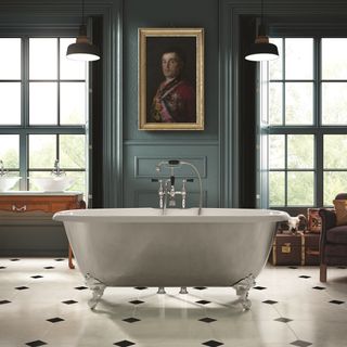opulent bathroom with green walls and large windows, a portait of a man in uniform on the wall, double vanity to the side and a freestanding rolltop clawfoot bath on top off white floor tiles with black diamond pattern