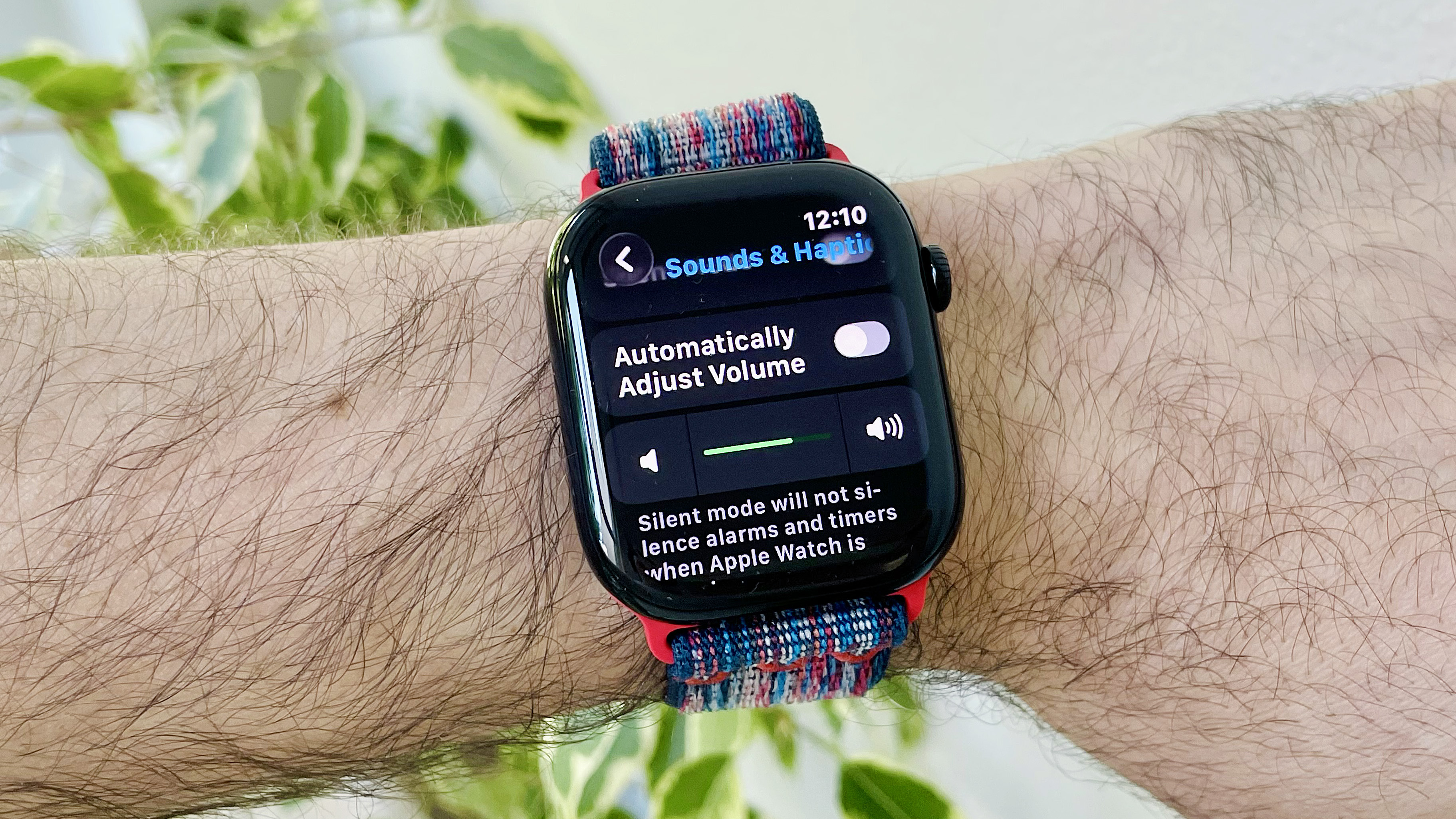 Close-up of a user's wrist wearing the Apple Watch Series 10 running the latest watchOS 26 software. The screen shows the new Automatic Audio Adjustments setting