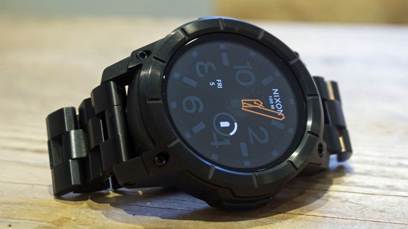 Nixon Mission usa smartwatch OS em uma mesa de madeira.