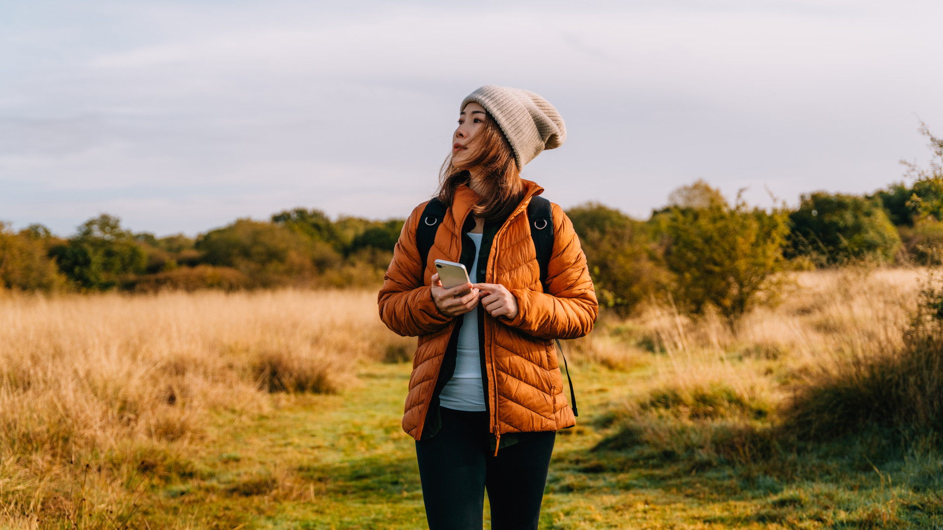 A woman on a walk using an outdoor app on her phone