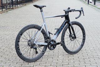 A grey and black bike stands on a brick pavement