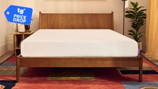 The PurpleFlex Mattress on a wooden bed frame in a bedroom, a Tom's Guide price drop deals graphic in the top right corner