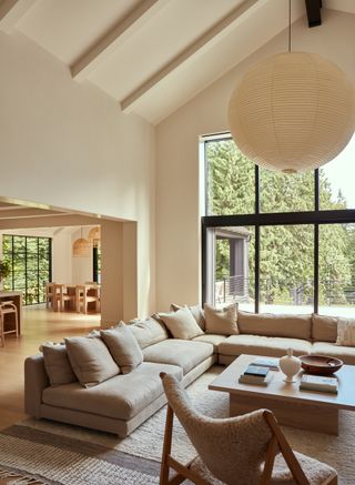 A large open plan living room in light neutral colors with a corner sofa and coffee table