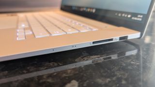The Zenbook S 16 photographed on a dark marble surface with potted plants in the background.