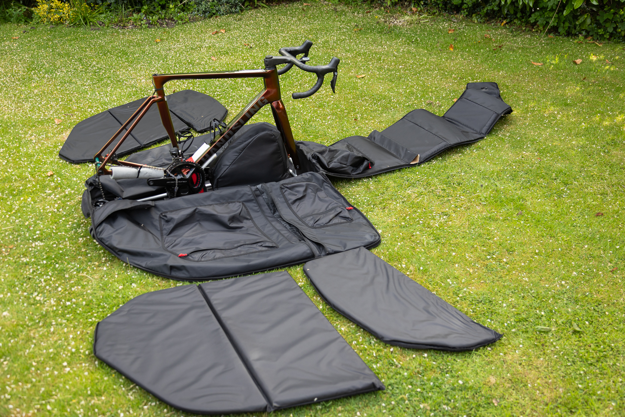 a bike frame fastened inside a bike bag with all the sides of the black bike bag opened out