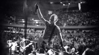 Bruce Springsteen performing live, surrounded by fans