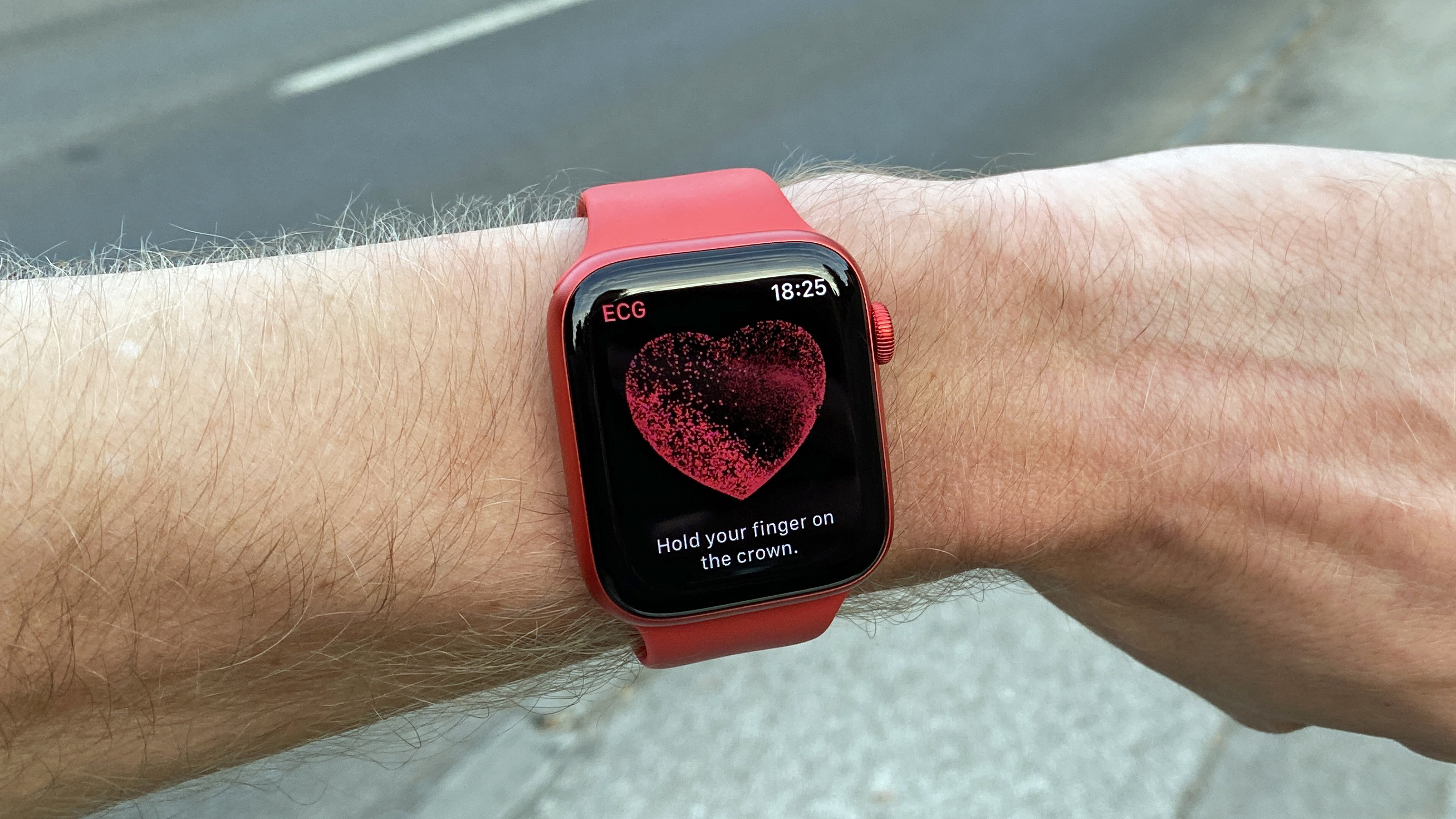 A red Apple Watch 6 on a wrist taking a heart rate reading