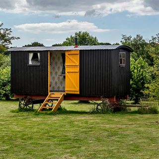 shepherd's hut with black exterior and trees