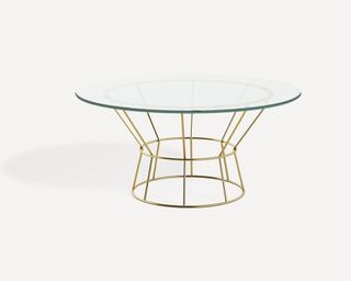 A round glass topped table with brass colored steel frame