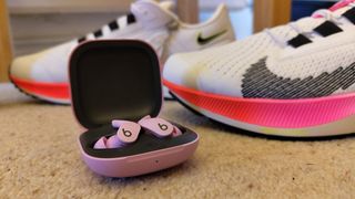 Beats Fit Pro in front of a pair of trainers