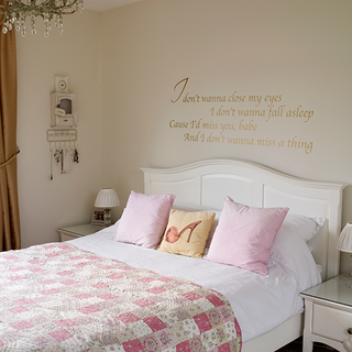 bedroom with lyrics on wall and cosy patchwork bedspread