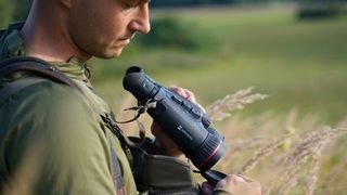 Hikmicro Habrok Pro binoculars being held by a man outdoors