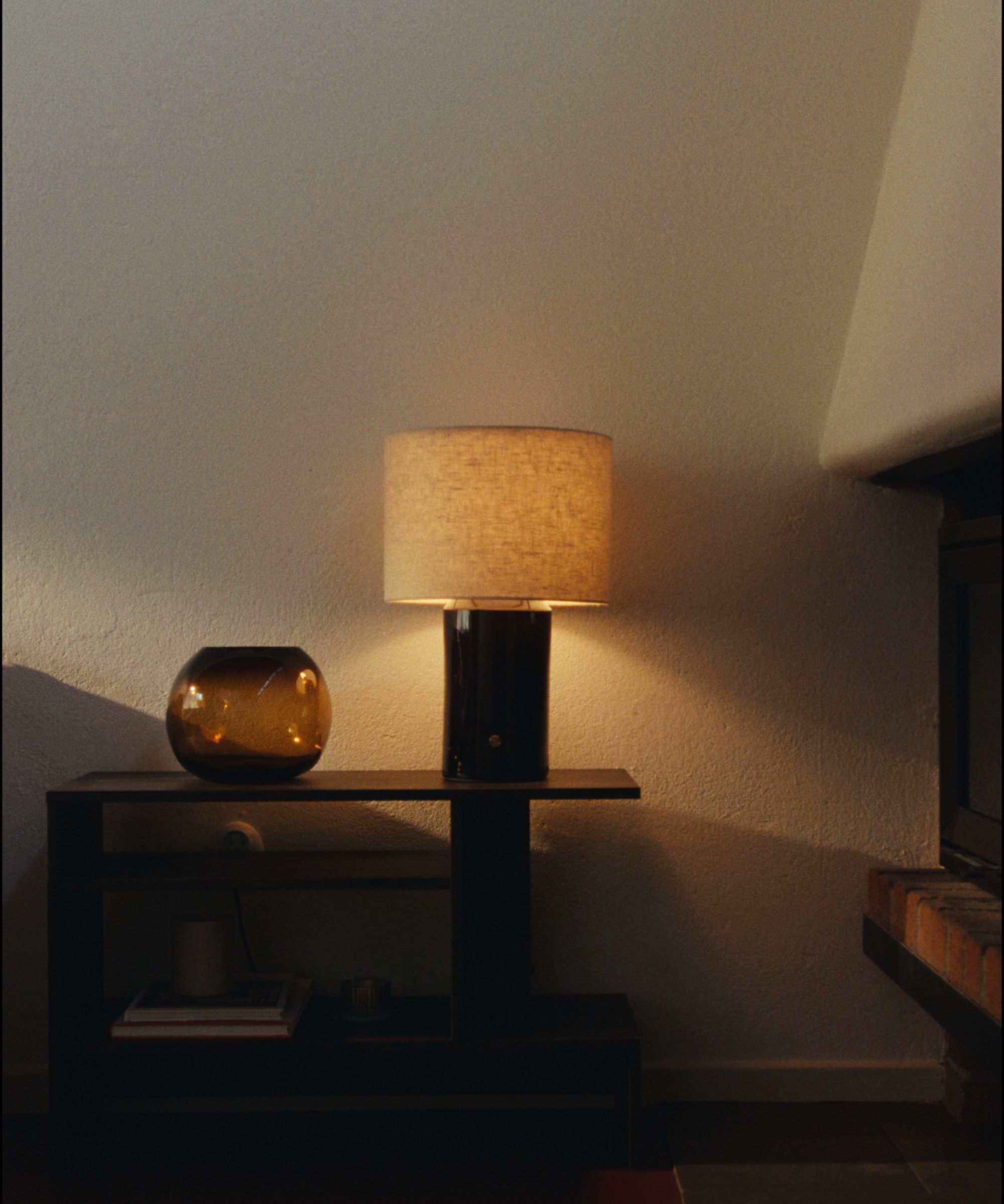 IKEA HALGATT lamp on a console table with an amber glass bowl beside it and books stacked on the tier below.