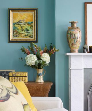 Pale blue living room, sofa, jug - vase of flowers, antique vase and painting