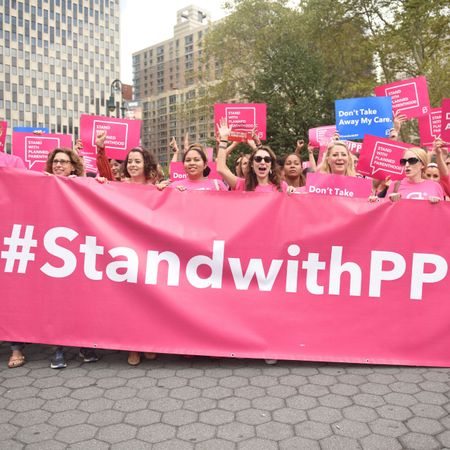 Protestors dressed in pink t-shirts holding aa banner that reads "#StandwithPP"