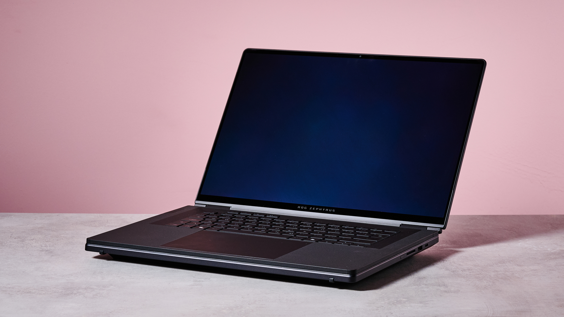 Three-quarter view of ASUS ROG Zephyrus Duo 2026 on a desk with pink wall in background