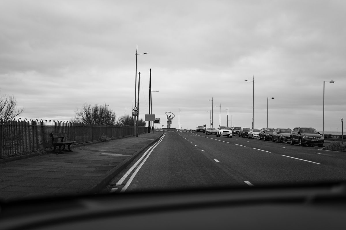 View out of a car windshield of a road with a statue in the distance